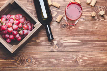 Bottle and glass of wine with grapes on wooden backgroundの写真素材