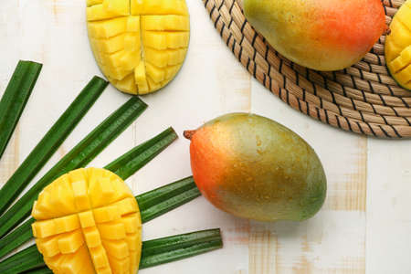 Sweet ripe mangoes on light wooden table