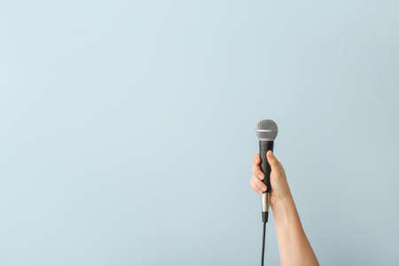 Female hand with microphone on color backgroundの写真素材