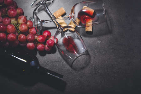 Bottle of wine with grapes, glasses and corks on dark backgroundの写真素材