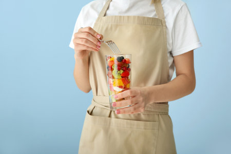 Woman eating tasty fruit salad on color background, closeupの写真素材