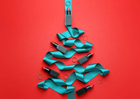 Beautiful Christmas tree made of lipsticks, rings and ribbon on color backgroundの写真素材