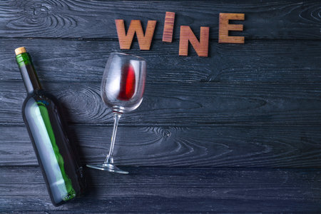 Bottle with tasty wine and glass on wooden tableの写真素材