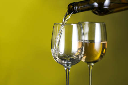 Pouring of tasty wine into against color backgroundの写真素材