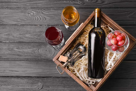 Box with bottle and glasses of different wine on wooden tableの写真素材