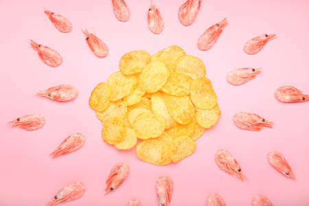 Composition with tasty potato chips and shrimps on color backgroundの写真素材