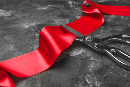 Scissors and red ribbon on grunge backgroundの写真素材