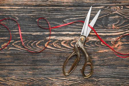 Scissors and red ribbon on wooden backgroundの写真素材