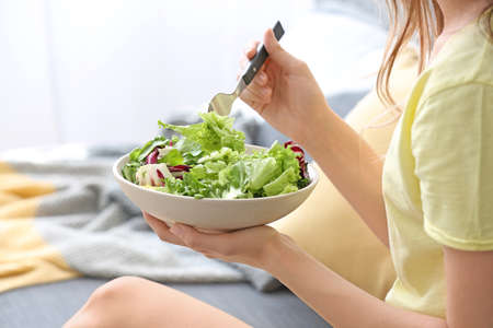 Woman eating healthy vegetable salad at homeの写真素材