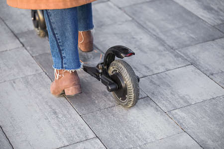 Young woman riding a kick scooter outdoors