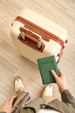 Young woman with packed suitcase and passport at home, top view