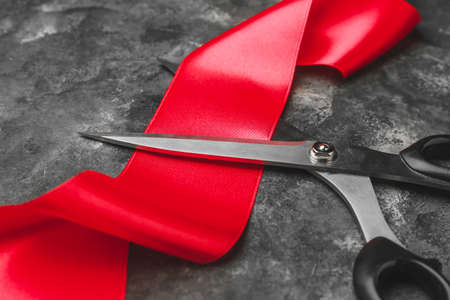 Scissors and red ribbon on grunge backgroundの写真素材