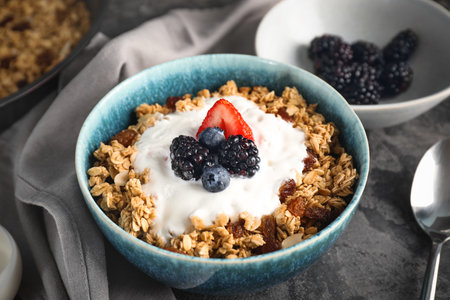Tasty granola with yogurt in bowl on gray backgroundの写真素材