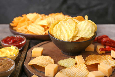 Bowl with tasty potato chips, cheese and sauces on tableの写真素材