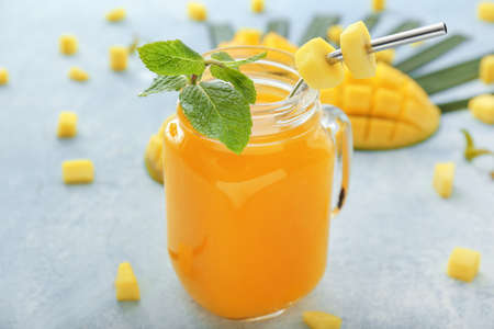 Mason jar of tasty mango juice on table