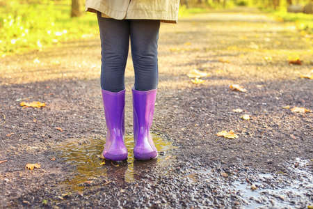 Cute little child wearing gumboots in autumn parkの写真素材