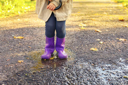 Cute little child wearing gumboots in autumn parkの写真素材