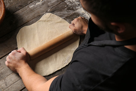 Man rolling out dough in kitchen
