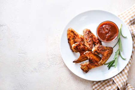 Plate with tasty fried chicken wings and barbecue sauce on white tableの写真素材