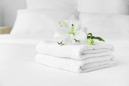 Clean soft towels and flowers on bedの写真素材