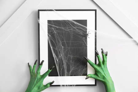 Hands of witch near photo frame indoors. Halloween celebrationの写真素材