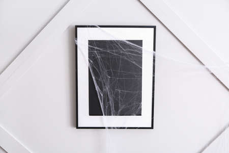 Frame with spider web hanging on wall