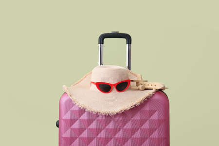 Packed suitcase, hat and glasses on color background. Travel conceptの写真素材