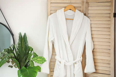 Soft clean bathrobe hanging on folding screen