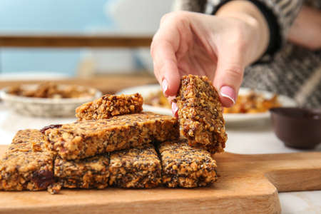 Woman taking tasty granola bar from table, closeupの写真素材