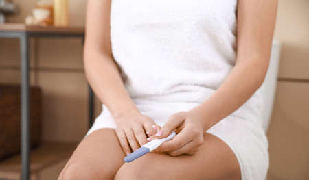 Young woman with pregnancy test in bathroom, closeupの写真素材