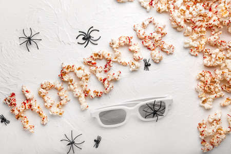 Composition with tasty popcorn and word HORROR on white backgroundの写真素材