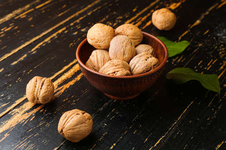 Bowl with tasty walnuts on wooden table