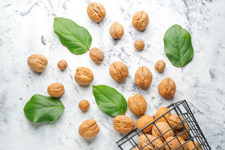 Basket with tasty walnuts on white background