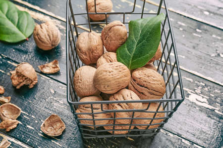 Basket with tasty walnuts on wooden table