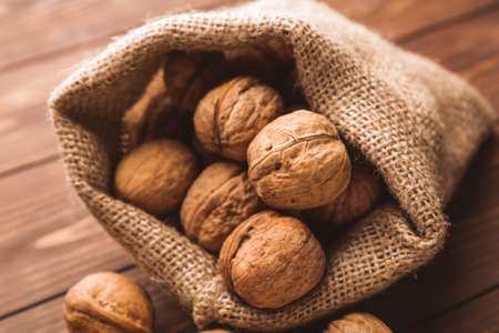 Sack with tasty walnuts on wooden tableの写真素材