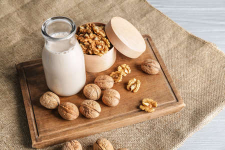 Bottle of milk with tasty walnuts on tableの写真素材