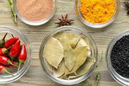Bowls with different spices on wooden background