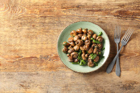 Plate with tasty cooked mushrooms and green beans on tableの写真素材