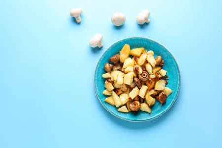 Plate with tasty cooked mushrooms and potato on color backgroundの写真素材