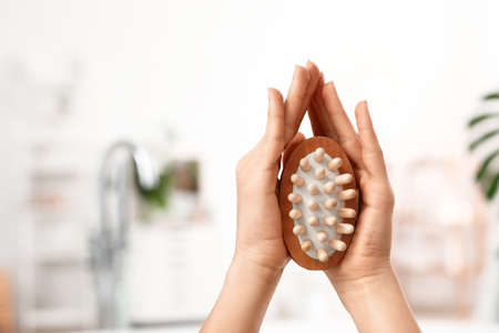 Hands of young woman with massage brush in bathroomの写真素材