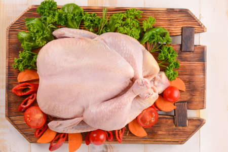 Raw chicken with chili and tomato on wooden backgroundの写真素材