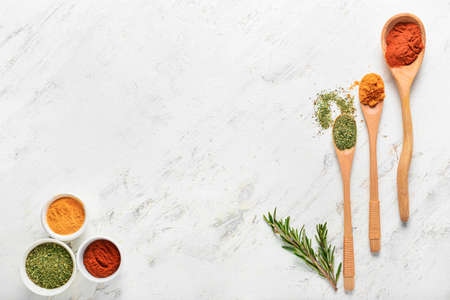 Spoons and bowls with different spices on white background