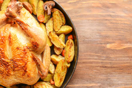 Dish with baked chicken and potato on wooden tableの写真素材