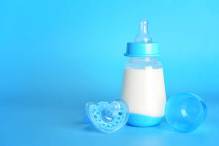 Bottle of milk for baby and pacifier on color backgroundの写真素材