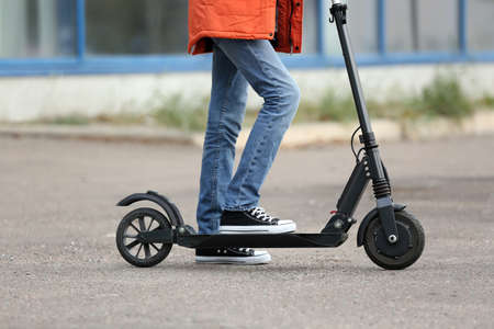 Teenage boy riding kick scooter outdoorsの写真素材