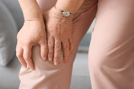 Senior woman suffering from pain in knee at home, closeupの写真素材