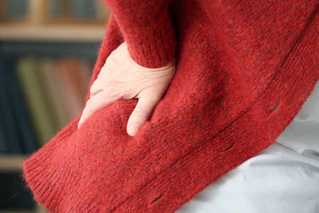 Senior woman suffering from back pain at home, closeup