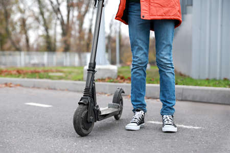 Teenage boy with kick scooter outdoorsの写真素材