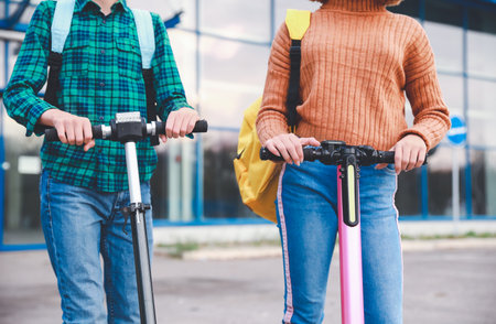Active teenagers riding kick scooters outdoorsの写真素材