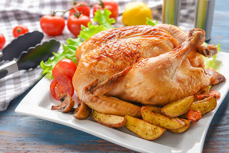 Plate with baked chicken and potato on tableの写真素材